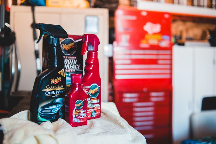 A collection of car-care cleaning product bottles displayed in a garage setting