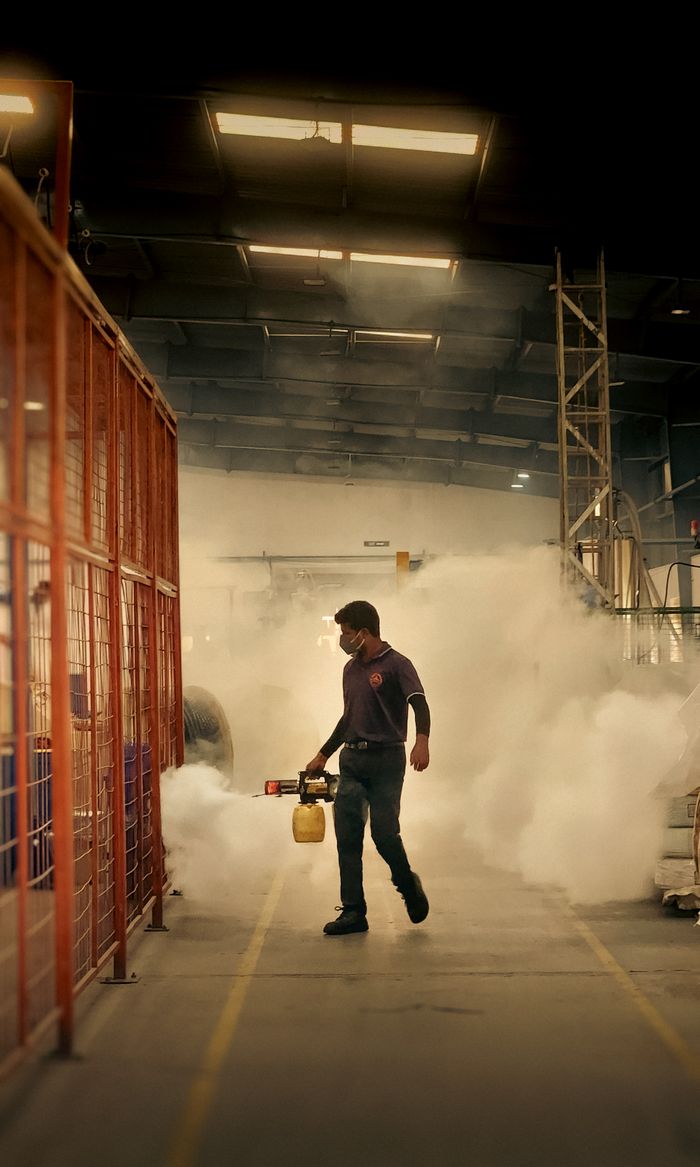A worker fumigating an industrial warehouse setting